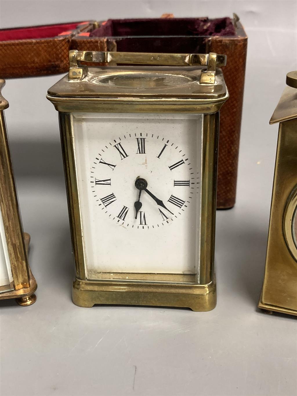 Three small gilt brass carriage timepieces, one with leather outer case, largest 10.5cm high